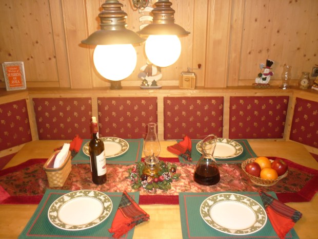 Our table decorations, in all their gaudy glamor.  How can a Christmas-themed table forego the classic red and green color combo? Throw in a burgundy velvet table runner (which happens to be a fashion trend in clothing form, sans glitter), oil lamp surrounded by holly, patterned napkins, and viola - a complete table arrives.